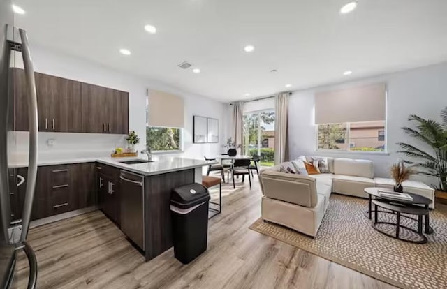 kitchen with appliances with stainless steel finishes, a breakfast bar, open floor plan, light countertops, and a sink