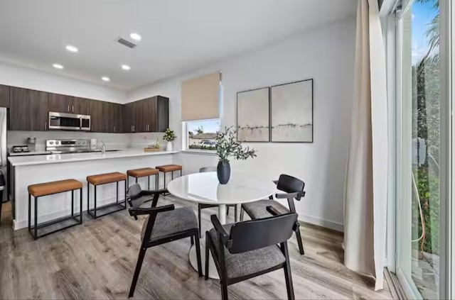 dining area featuring light wood finished floors, recessed lighting, visible vents, and baseboards