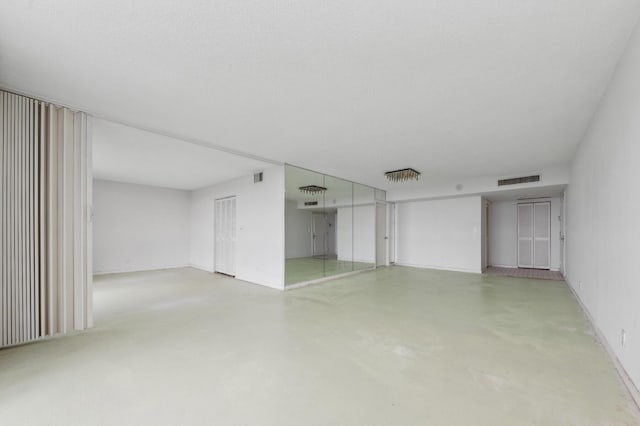 empty room with visible vents, concrete flooring, and baseboards