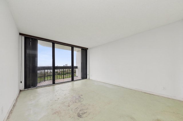 unfurnished room with floor to ceiling windows, baseboards, and concrete flooring