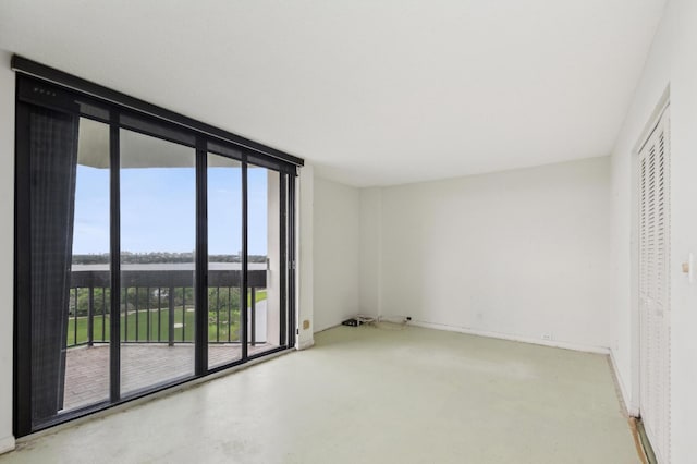 unfurnished room featuring a wall of windows, baseboards, and concrete flooring