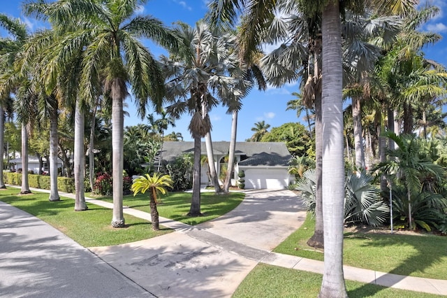 view of front of home with a garage, a front lawn, and concrete driveway