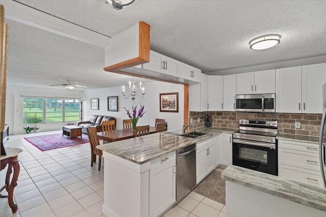 kitchen with tasteful backsplash, white cabinets, appliances with stainless steel finishes, open floor plan, and a peninsula