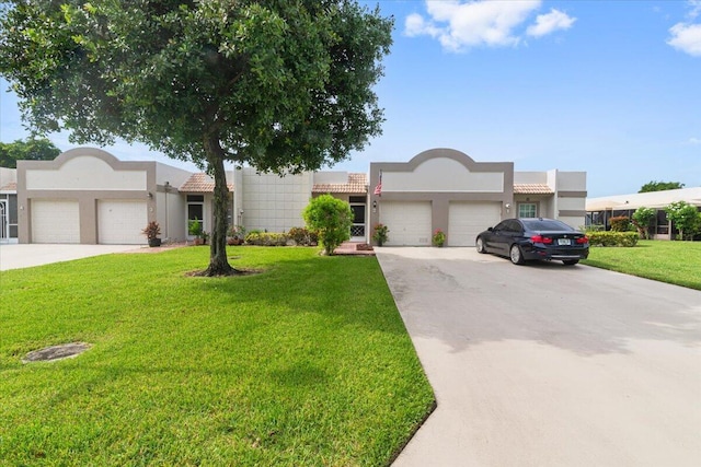 pueblo revival-style home with an attached garage, concrete driveway, and stucco siding