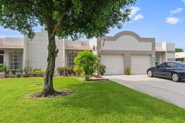 southwest-style home featuring a garage, driveway, a front lawn, and stucco siding