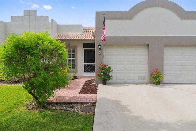 view of front facade featuring concrete driveway, an attached garage, a tiled roof, and stucco siding