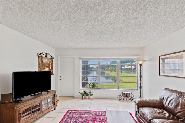 living room featuring a water view, a textured ceiling, and light tile patterned floors