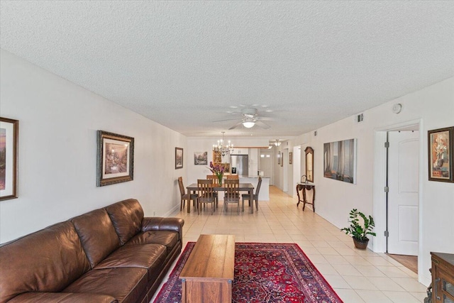 living room with ceiling fan with notable chandelier, visible vents, a textured ceiling, and light tile patterned floors