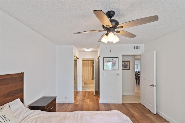 bedroom featuring a textured ceiling, light wood-type flooring, visible vents, and baseboards