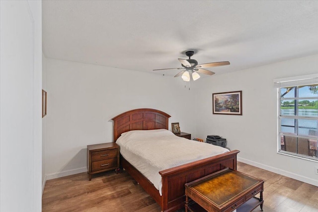 bedroom with ceiling fan, baseboards, and wood finished floors