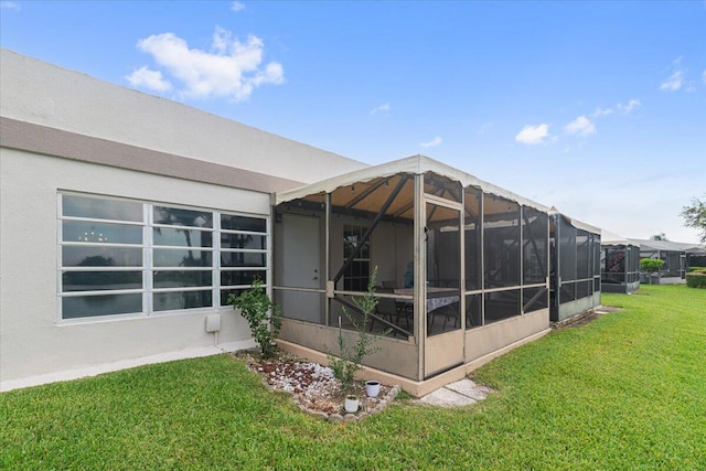 rear view of property with a lawn and stucco siding