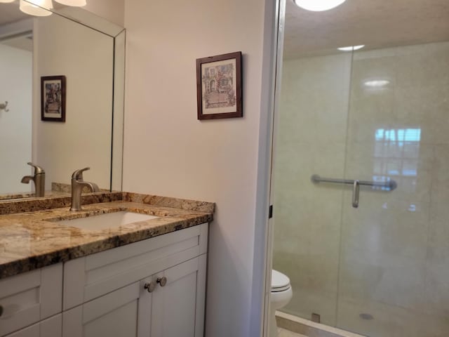 full bathroom with vanity, a shower stall, and toilet