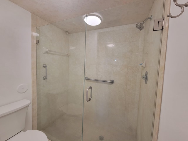 bathroom featuring a shower stall and toilet