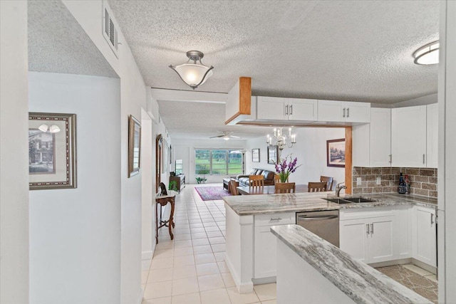 kitchen with a peninsula, a sink, white cabinets, open floor plan, and stainless steel dishwasher