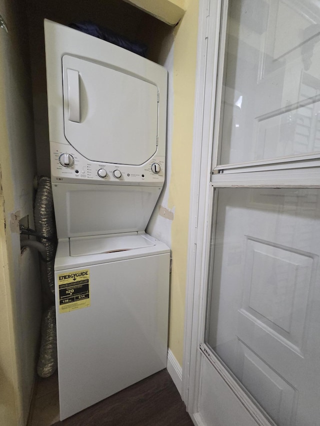 washroom featuring laundry area, dark wood-type flooring, and stacked washer / dryer