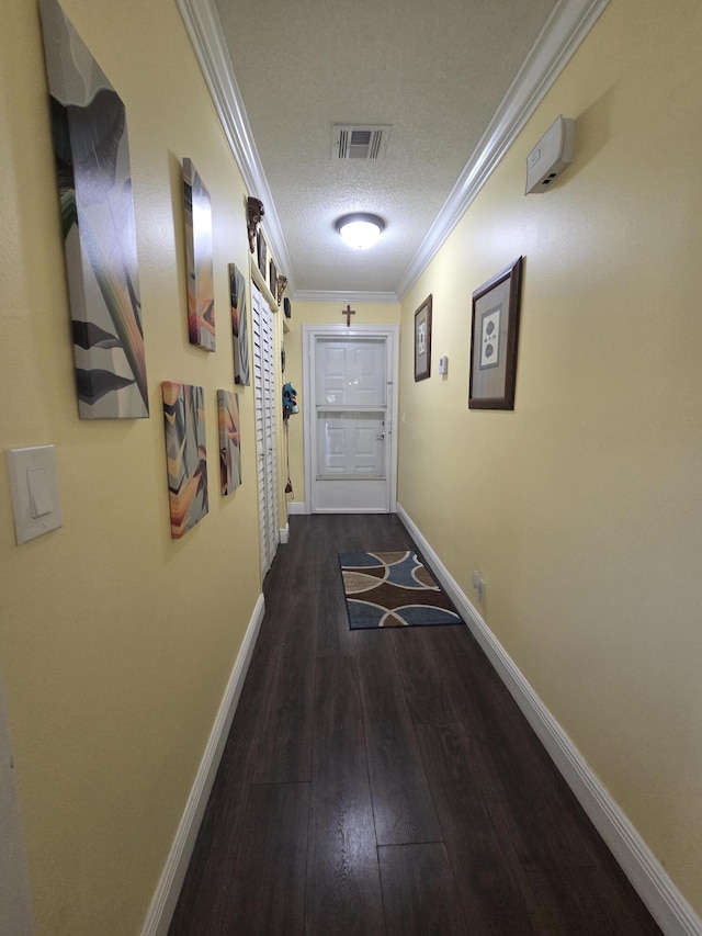 hall with ornamental molding, wood-type flooring, visible vents, and baseboards