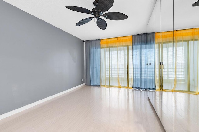 spare room featuring light wood-style floors, baseboards, and a ceiling fan