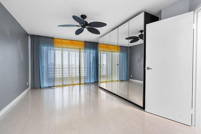 unfurnished room with light wood-style floors, a ceiling fan, and baseboards