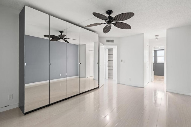 unfurnished bedroom featuring light wood finished floors, baseboards, visible vents, and a textured ceiling