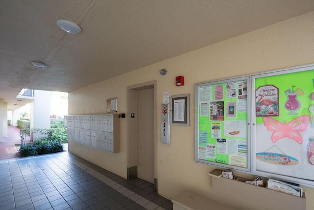 interior space with elevator, dark tile patterned floors, and mail area