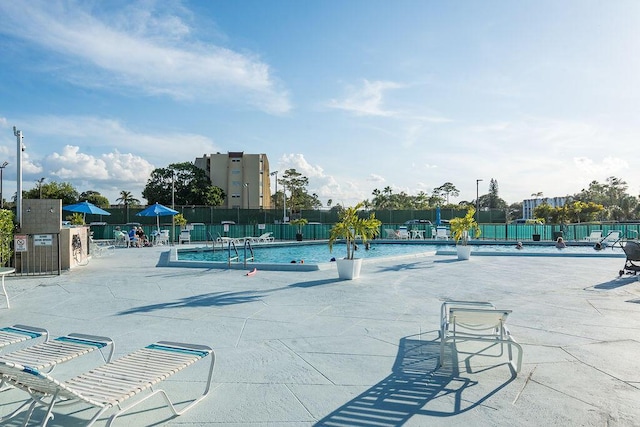 view of home's community with a swimming pool, fence, and a patio