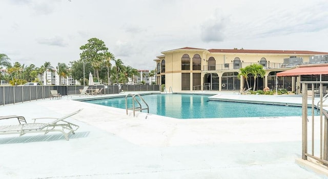 community pool with a patio area and fence