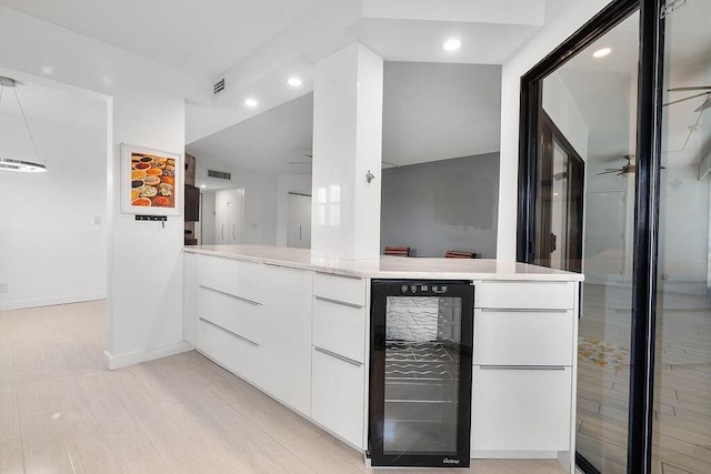 interior space featuring ceiling fan, wine cooler, wood finished floors, and visible vents