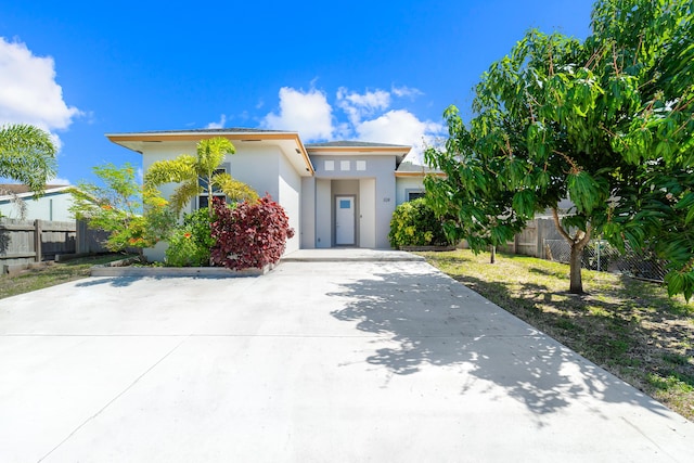 prairie-style house featuring concrete driveway, a front yard, fence, and stucco siding