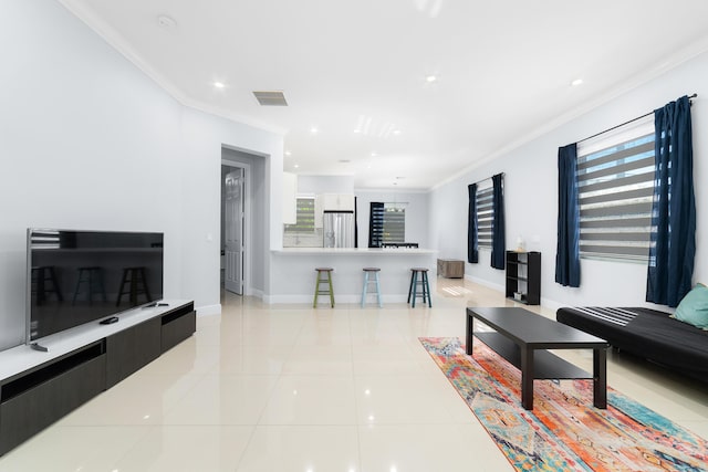 living room with light tile patterned floors, baseboards, visible vents, and crown molding