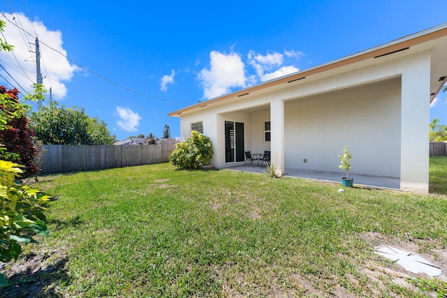 rear view of house featuring a yard, fence, and a patio