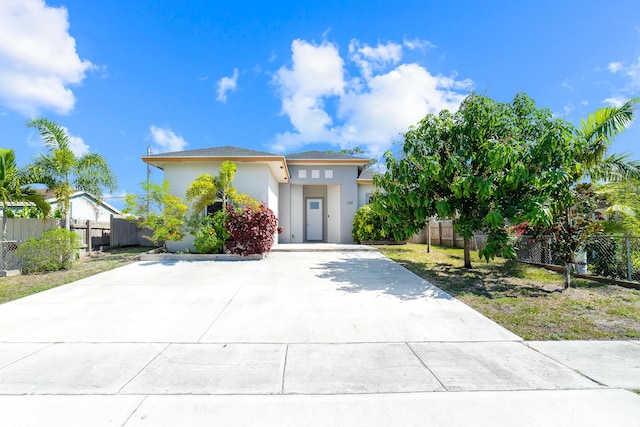 view of front facade featuring concrete driveway, fence, and stucco siding