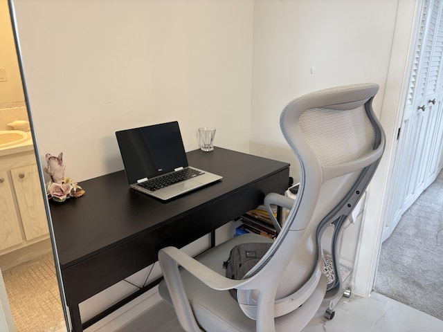 office with light carpet, marble finish floor, and a sink