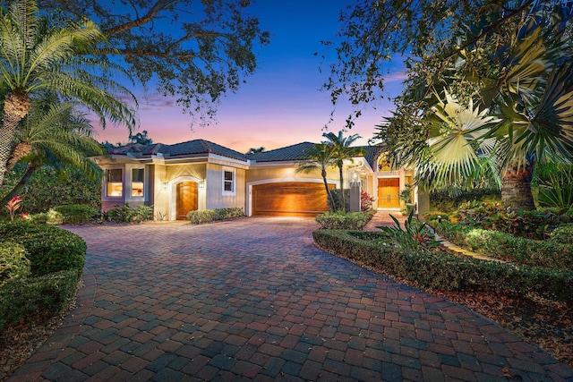 view of front facade with a garage, decorative driveway, and stucco siding