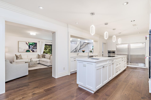 kitchen featuring open floor plan, black electric stovetop, light countertops, white cabinets, and a sink