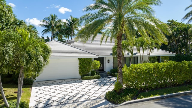 view of front of house featuring a garage, concrete driveway, a tile roof, and stucco siding