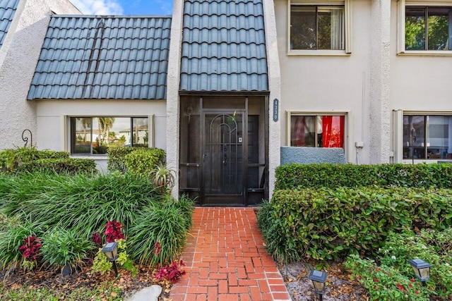 property entrance with a tile roof and stucco siding