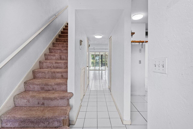 staircase with tile patterned flooring, a textured wall, and baseboards