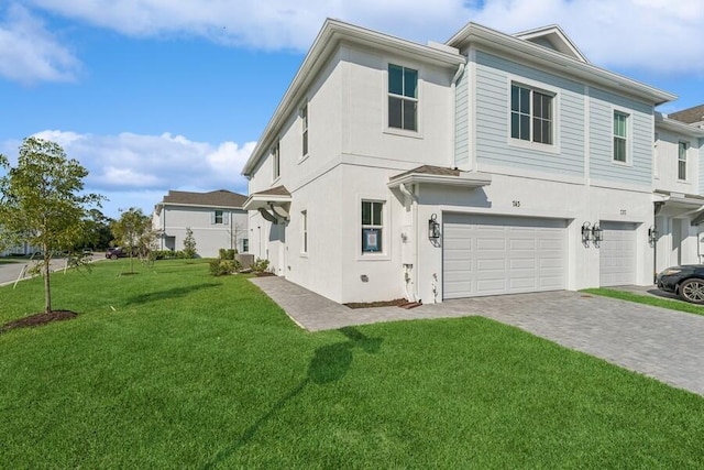 exterior space featuring a garage, decorative driveway, a lawn, and stucco siding