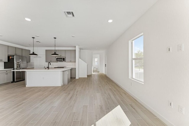 kitchen with stainless steel appliances, gray cabinets, light countertops, visible vents, and light wood-style floors