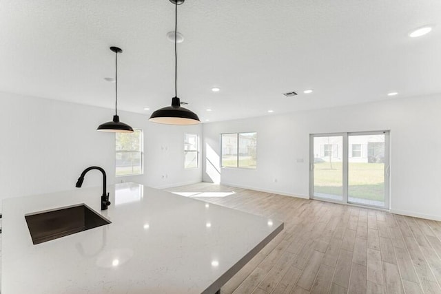 kitchen with light wood finished floors, recessed lighting, a sink, and decorative light fixtures