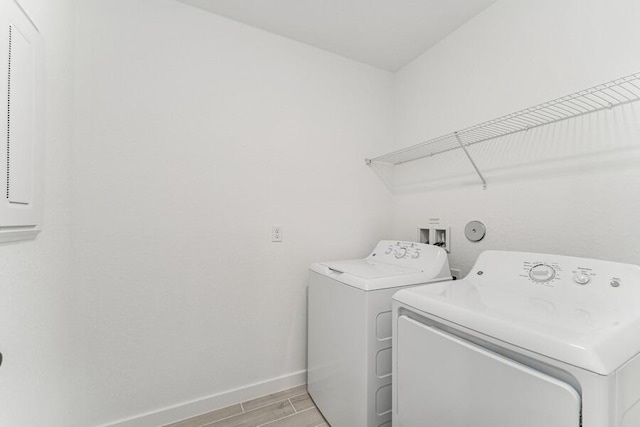 clothes washing area with baseboards, laundry area, wood tiled floor, and washer and dryer