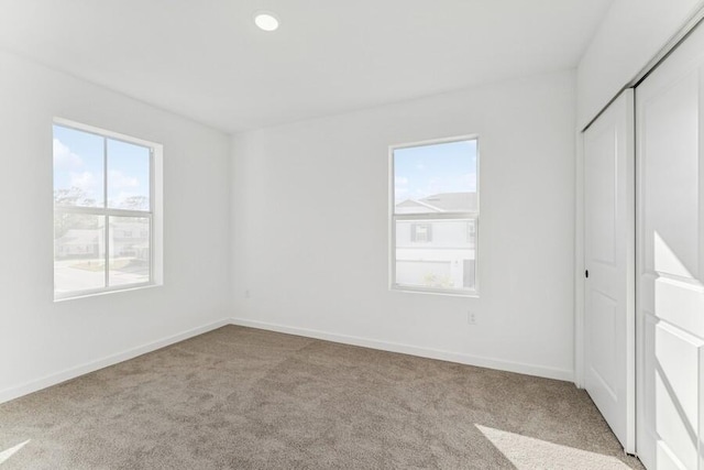 unfurnished bedroom with carpet, a closet, baseboards, and recessed lighting