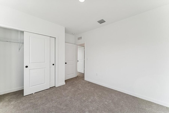 unfurnished bedroom featuring baseboards, a closet, visible vents, and carpet flooring