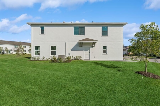 rear view of house with a lawn, stucco siding, and central air condition unit