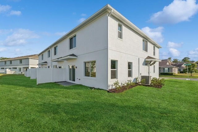 back of house featuring stucco siding, a residential view, fence, and a yard