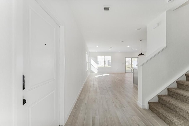 hallway with visible vents, baseboards, light wood-style flooring, stairs, and recessed lighting