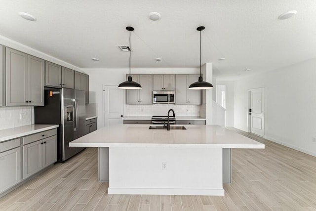 kitchen with appliances with stainless steel finishes, gray cabinets, a sink, and wood tiled floor