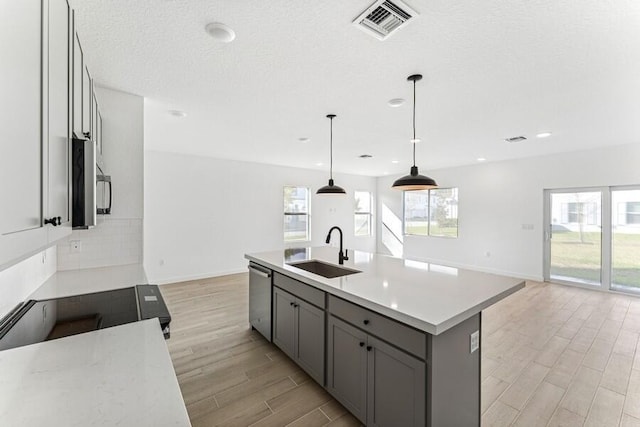 kitchen with visible vents, appliances with stainless steel finishes, gray cabinets, light wood-type flooring, and a sink