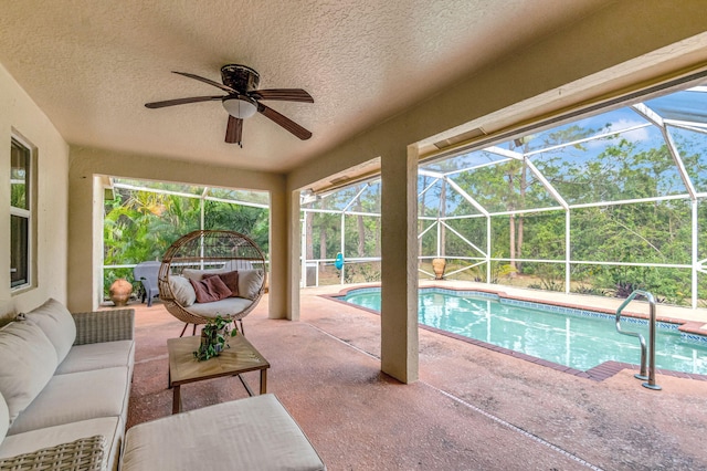 pool featuring glass enclosure, outdoor lounge area, a ceiling fan, and a patio