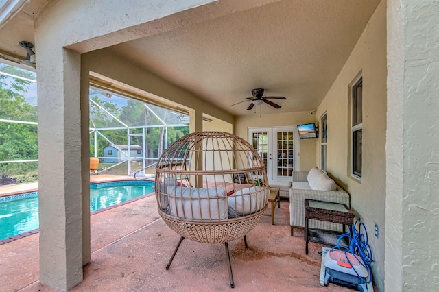 view of patio / terrace featuring french doors, a ceiling fan, glass enclosure, an outdoor pool, and an outdoor living space